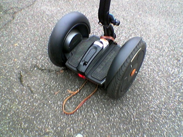 Gurtloesung: vorne ueber die Lenkstange und anderes Ende der Schlaufe unter dem Segway durchlaufen lassen und daran heben.